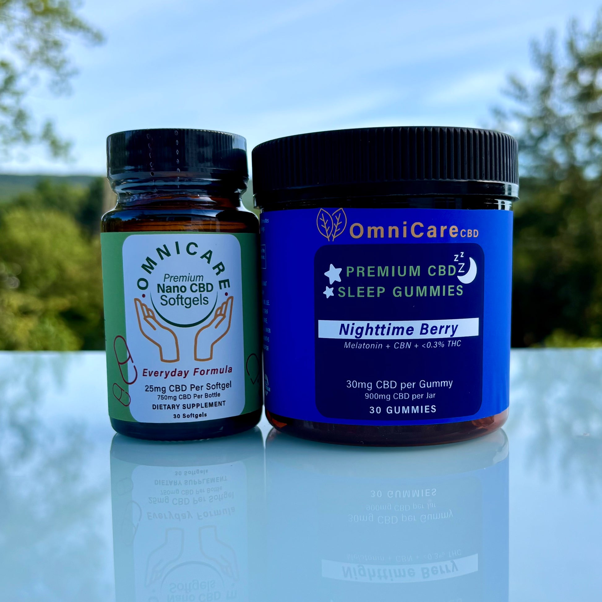 24/7 Wellness Bundle featuring Everyday Formula CBD Softgels for daytime balance and CBN + THC Sleep Gummies for restful sleep on a white surface with a blurred natural background.