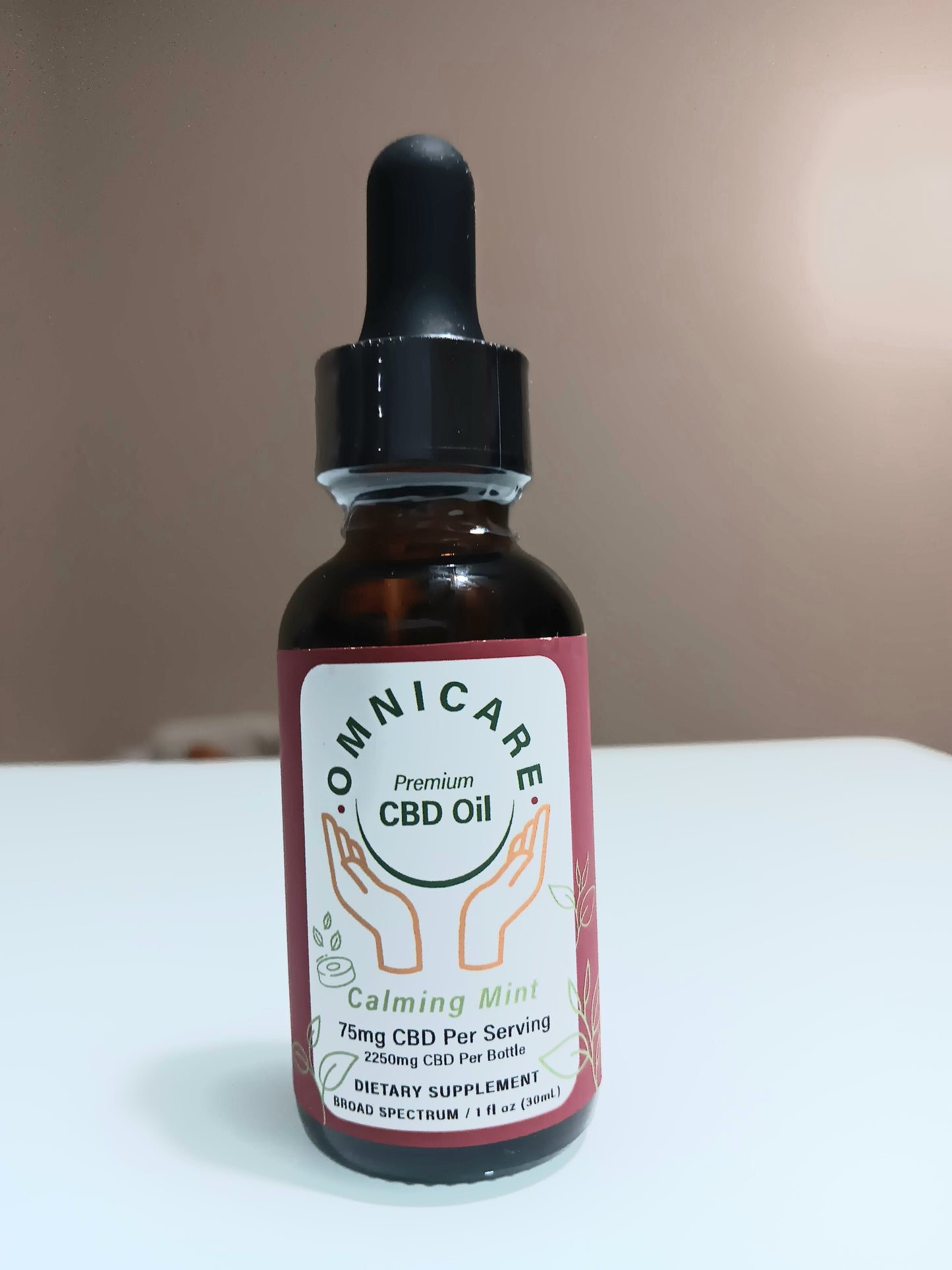 Organic CBD Tincture – Calming Mint flavor 75MG from OmniCare CBD on a white surface with a tan background.