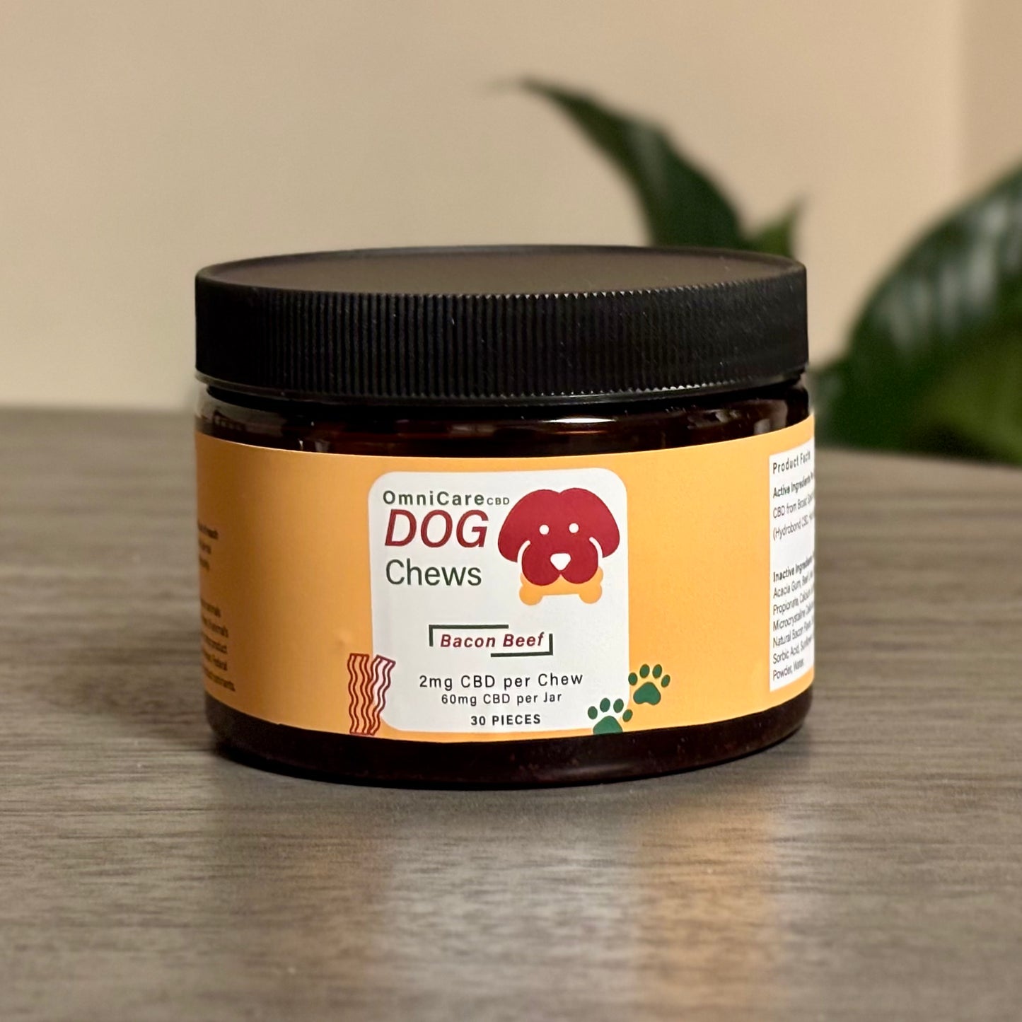 CBD Dog Chews – 25mG Beef flavor on a wood surface from OmniCare CBD on a wooden surface with a plant in the background.